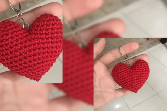 Hand holding a bright red crocheted heart keychain attached to a metal ring.