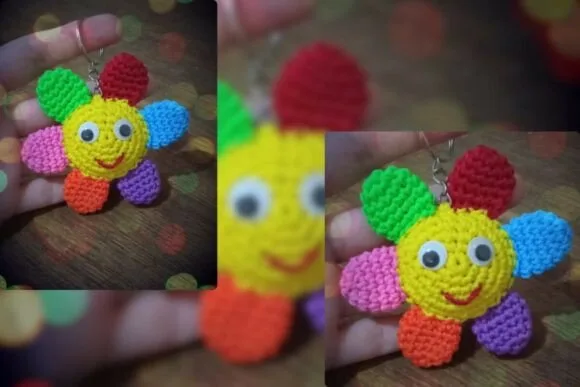 Colorful handmade crochet flower keychain with googly eyes held in a hand